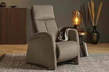 Grauer Relaxsessel mit hohen Armlehnen und hoher Rückenlehne in einem gemütlichen Raum mit Beistelltisch und Tischlampe und großer Vase mit Pampasgras.