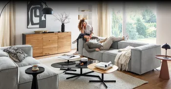 Pärchen sitzt gemütlich auf Couch in modern eingerichteten Wohnzimmer.