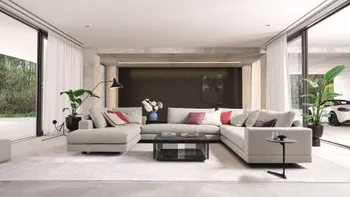 Graue moderne Wohnlandschaft mit breiten grauen Rückenkissen und schwebender Optik, auf dem Sofa liegen mehrere bunte Kissen.