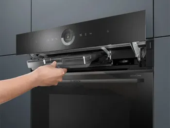 Backofen von Bosch, das Bedienfeld ist nach oben geklappt und eine Hand entnimmt den Filter. 