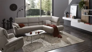 Graues Ecksofa mit hoher Rückenlehne und dazu passendem Sessel.