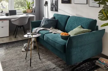 Smaragdgrünes Sofa mit Rautenmuster an den Rückenkissen.