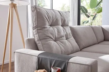 Hellgraues Sofa mit großem gesteppten Rückenkissen.