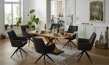 Sie sehen ein Esszimmer mit Tisch in Eiche Mittelfuß in Eiche und dunklen Armlehnstühlen 