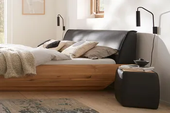 Gemütliches Schlafzimmer mit Doppelbett und passendem Nachttisch in schwarzem Leder.
