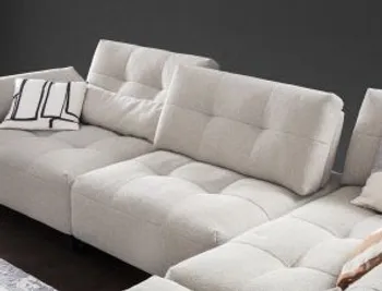 Beiges modernes Sofa mit Steppung vor einer dunklen Wand.