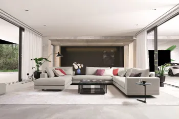 Große moderne graue Wohnlandschaft mit tiefer Sitzfläche und bequem gepolsterten Rückenkissen in einem hellen Raum.