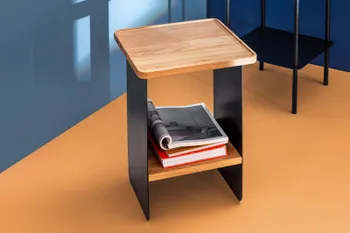 Beistelltisch OLAI von RAM.FREUNDE aus schwarzem Metall mit Eicheplatte in Interior mit blauer Wand und gelbem Boden
