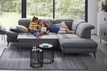 Graues Ecksofa mit erweiterter Sitzfläche, auf dem eine Frau und zwei Kinder gemütlich sitzen.