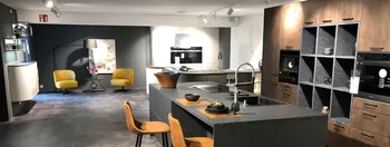 Moderne Küche in Betonoptik. Im Hintergrund sieht man weitere Ausstellungsmöbel des Küchenstudios.