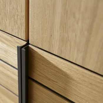 Tür eines Kleiderschranks aus Massivholz mit schwarzen Metallgriff aus der Nähe.