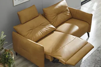 Gelbes Ledersofa mit hochgeklappter Fußlehne und nach hinten gestellter Rückenlehne in einem hellen Raum.