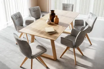Heller minimalistischer Esstisch aus Massivholz mit Kufen und dekoriert mit Vasen, um den graue Schalenstühle mit und ohne Armlehne stehen.