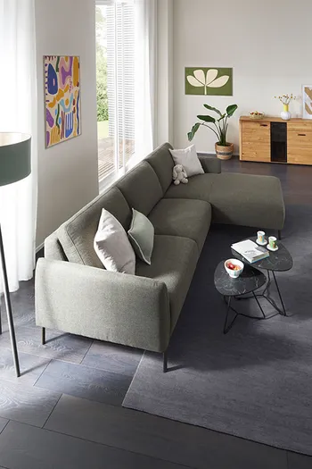 Vogelperspektive auf grünes Ecksofa in gemütlichem Wohnzimmer.