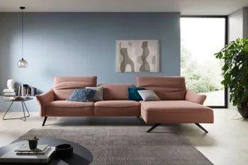 Rosafarbendes Ecksofa mit schwarzen Metallfüßen in einem hellen Wohnzimmer mit schwarzem Beistelltisch.