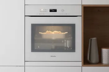 Weißer erhöht eingebauter Einbaubackofen von Miele.