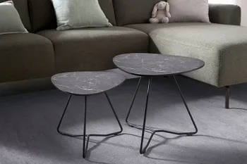 Zwei schwarze Beistelltische mit schwarzem Metallgestell vor einem Sofa.