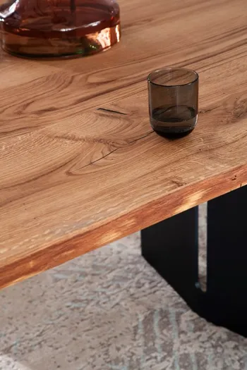 Teil eines modernen Massivholz Esstisches mit schwarzem Gestell.