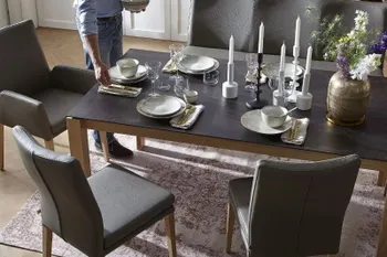 Dunkelgraue Sitzbank und Lederstühle um einen Esstisch mit schwarzer Tischplatte.