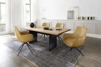 Modernes Esszimmer in dem ein Design Esstisch mit einer Massivholz Tischplatte und einem schwarzen Metallfuß steht, um den Tisch stehen Schalenstühle mit gelbem Lederbezug und schwarzem Fußgestell.