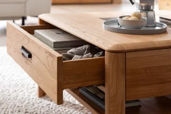 Ein Couchtisch aus Massivholz mit geöffneter Schublade und Ablagefach darunter.