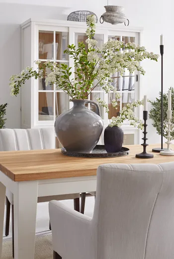 Esstisch mit großer Vase und ausladenden grünen Blumen