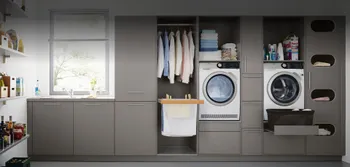 Hauswirtschaftsraum mit grauen Fronten, Waschmaschine und Lagerraum. 
