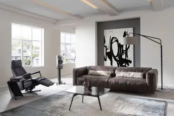 Braunes Ledersofa dekoriert mit zwei länglichen beigen Kissen in modernem hellen Wohnzimmer mit Glascouchtisch.
