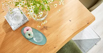 Massivholztisch dekoriert mit Blumen und Tablett mit Donuts.