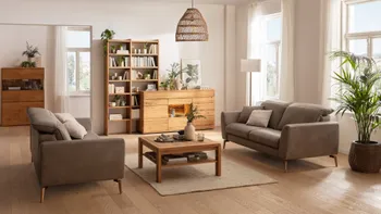 Zwei graue Ledersofas mit umgeklappter Kopfstütze, die sich gegenüber stehen in einem gemütlichen Wohnzimmer mit Couchtisch, Regal und Sideboard aus Holz dekoriert mit vielen Pflanzen.