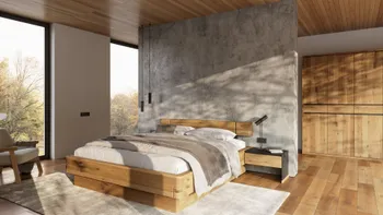 Bett aus Massivholz vor einer Wand im Beton Optik, daneben ein Kleiderschrank ebenfalls aus Massivholz in einem gemütlichen sehr hellen Schlafzimmer.