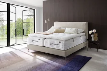 Boxspringbett mit beigem Boucle Bezug auf dem zwei Sleepeezee Matratzen liegen und ein Topper darauf und weiße und beige Kissen und eine Decke.