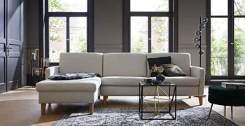 Gemütliches graues Sofa mit Holzfüßen in einem hellen Raum.