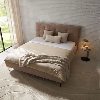 Beiges Designer Polsterbett mit gestepptem Kopfteil und Beistelltisch mit Lampe.