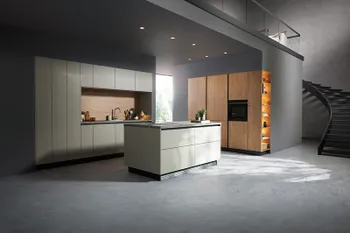 Elegante Inselküche mit matter, hellgrauer Oberfläche und warmen Holzelement.