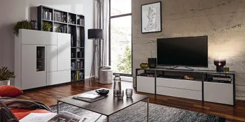 Weiße Wohnwand mit Fernseher und schwarzen Akzenten in gemuetlichem Wohnzimmer.