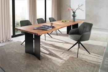 Designer Massivholz Esstisch mit Baumkante und schwarzem Gestell, um den grüne Schalenstühle stehen in einem hellen Raum.