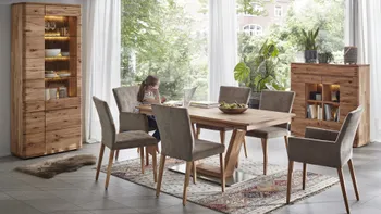 Esszimmertisch, Vitrine und Highboard aus Massivholz in einem gemütlichen Esszimmer, ein Mädchen sitzt am Esstisch vorm Laptop.