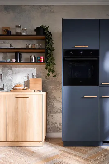 Detailbild von blauem Küchenhochschrank mit integriertem Backofen und Küchenzeile mit Holzfronten.