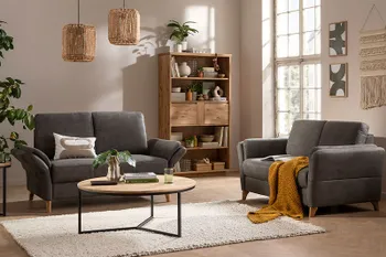 Gemütliches Wohnzimmer mit zwei Zweisitzer-Sofas in dunklem Grün, rundem Couchtisch und Regal aus Massivholz.
