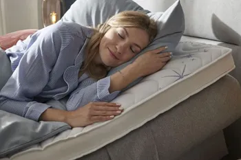 Frau liegt in einem Bett, bei dem die Matratze höher gestellt ist.