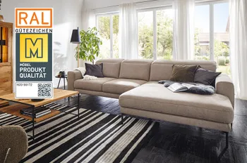 Siegel &quot;Goldene M&quot; auf einem Bild eines modernen beigen Ecksofas mit schwarzem Fußgestell und umgeklappter Rückenlehne.