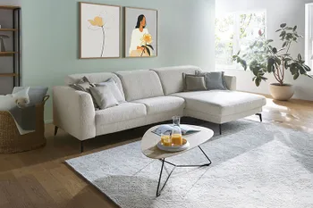 Beiges Ecksofa mit klappbaren Rückenlehnen und filigranen schwarzen Füßen.