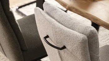 Freischwinger Stuhl in grau mit schwarzem Metallgriff an der Rückenlehne.
