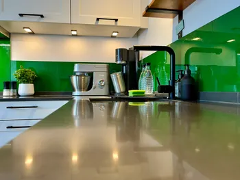 Detailansicht der Arbeitsplatte aus dunklem Quarzstein. Im Hintergrund sieht man Küchengeräte und einen Wasserhahn