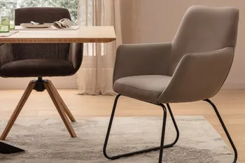 Ein beiger Schalenstuhl mit schwarzem Metallgestell neben einem grauen Schalenstuhl mit einem Holzgestell.