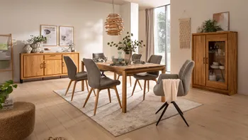 Moderne graue Stühle mit holzgestell und zwei graue Armlehnstühle mit schwarzem Metallgestell um einen Massivholzesstisch.