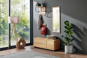Moderne Garderobe aus hellem Holz in luftiger Optik mit Schubank mit Schubläden, Spielgel, Hutablage und Kleiderhaken vor einer grauen Wand.