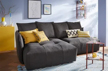 Dunkelgraues Sofa mit vielen Kissen am Rücken und gelben Dekokissen.