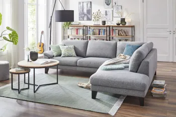 Hellgraues Ecksofa mit dicken Rückenkissen und schwarzen Füßen.